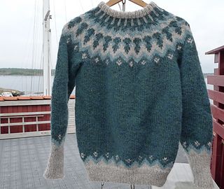 Hand-knitted teal oversized unisex Scandinavian Lopapeysa sweater with a chunky-knit beige and blue Nordic round yoke, featuring a double crew neck, beige ribbed cuffs, and hem, made from soft hypoallergenic baby alpaca and merino wool.