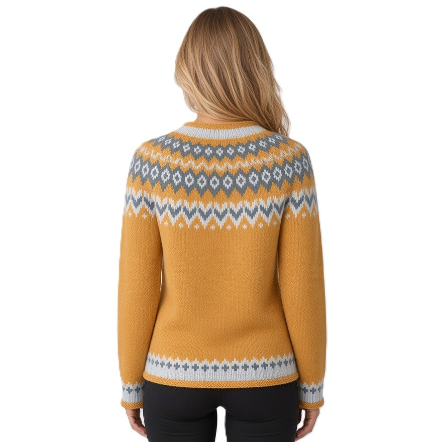 A woman viewed from the back wearing a mustard yellow knit sweater with a gray and white Fair Isle pattern across the shoulders, collar, cuffs, and hem, paired with black pants against a white background.