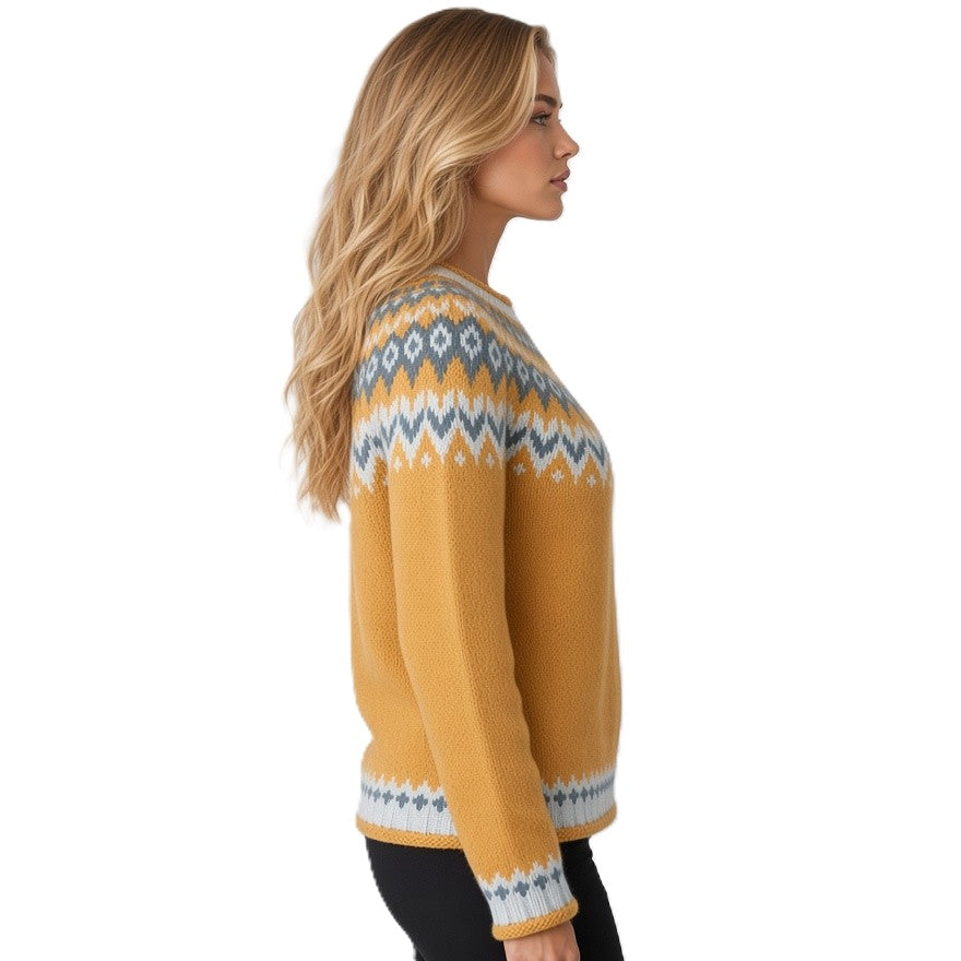 A woman shown in side profile wearing a mustard yellow knit sweater with a blue and white geometric Fair Isle pattern across the shoulders, upper chest, and cuffs, against a plain white background.