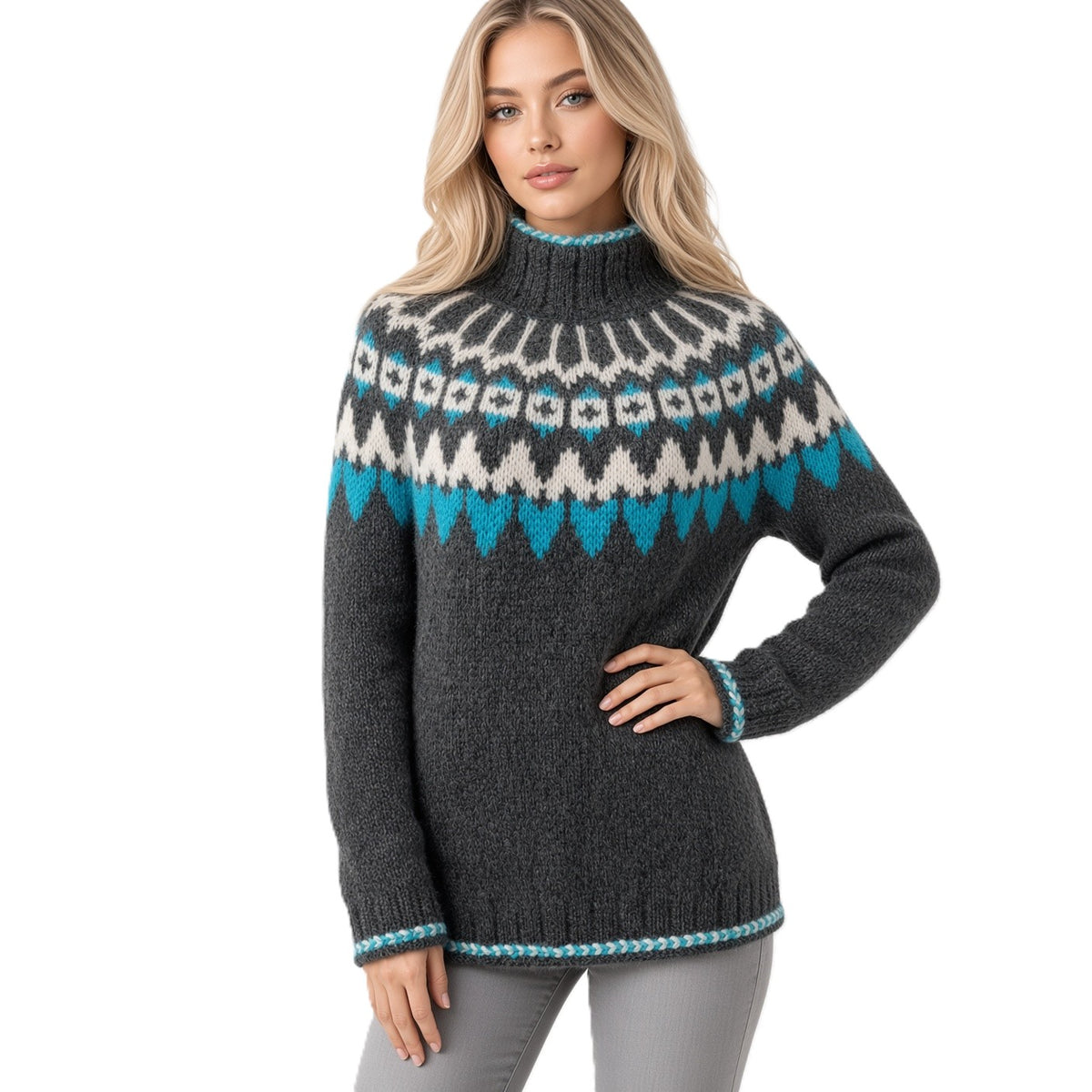 A woman modeling a dark gray knit sweater with a colorful Fair Isle pattern across the chest and shoulders in white, light gray, and turquoise blue, paired with gray pants against a plain white background.