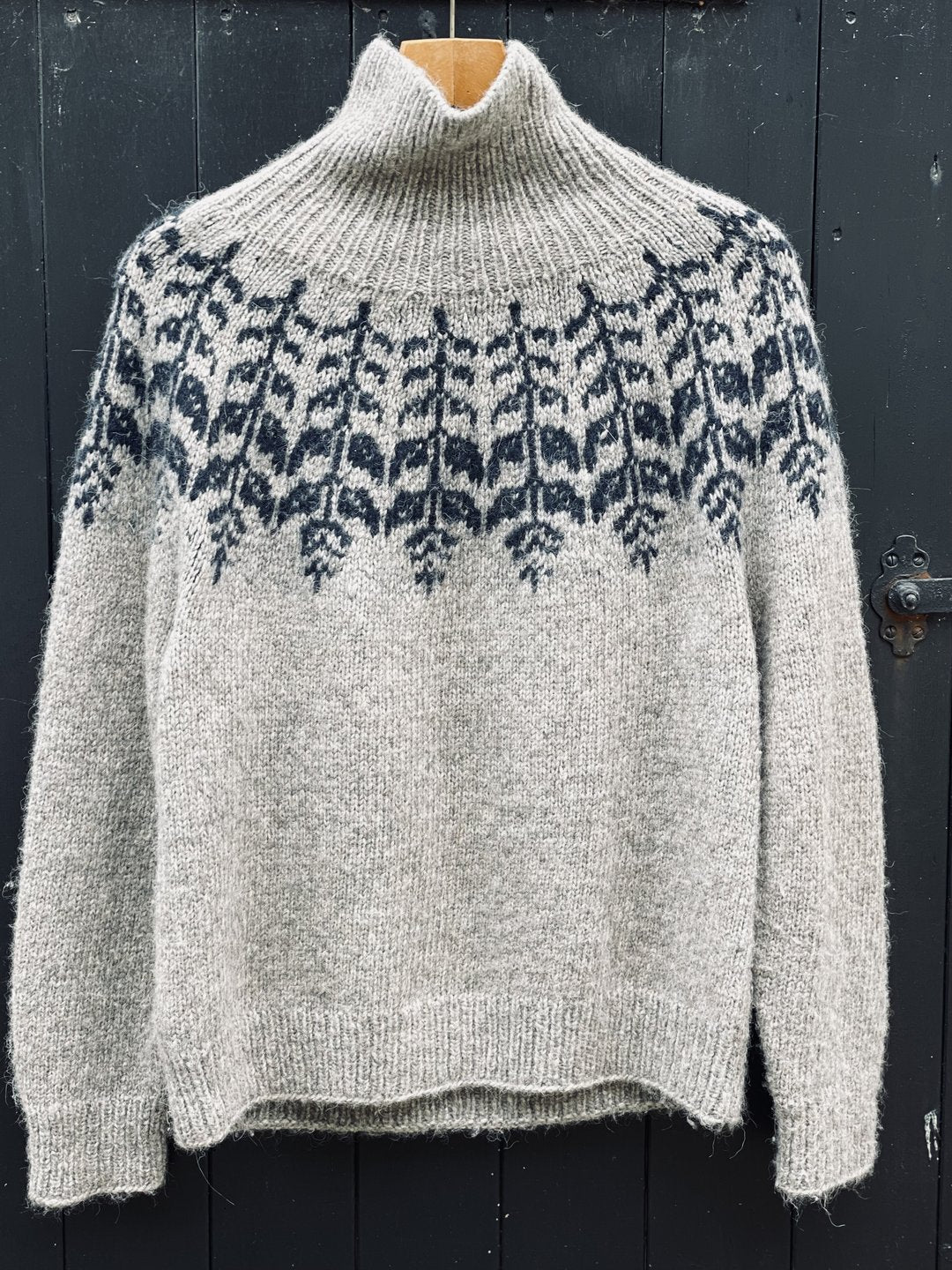 Knitted sweater with a patterned yoke against a dark background
