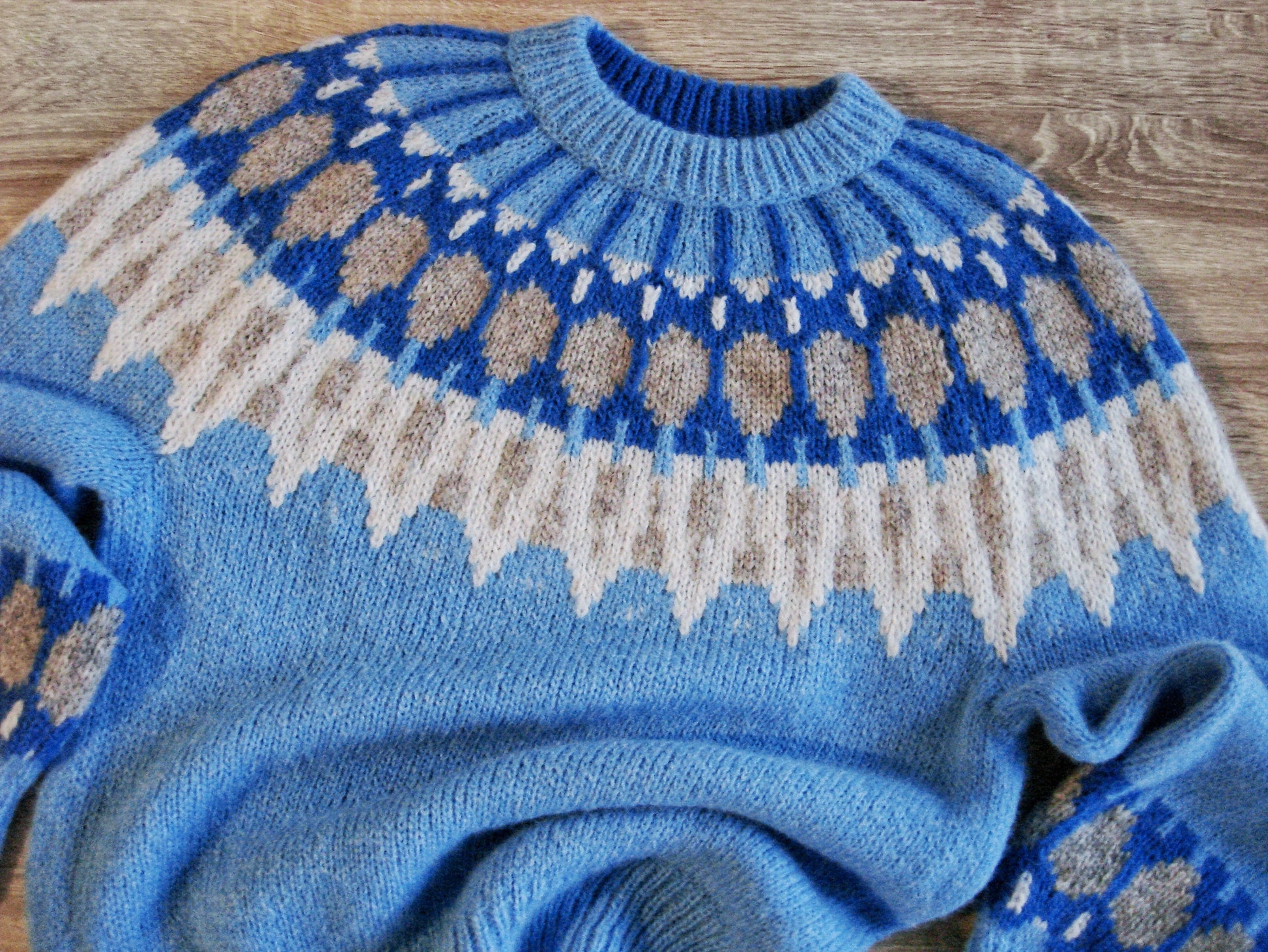 Hand-knitted women’s Scandinavian Lopapeysa sweater in Blue, featuring a harmonizing White, Beige & Electric Nordic round yoke, with ribbed hem, cuffs, and double crew collar in Blue, made from soft hypoallergenic baby alpaca and merino wool.