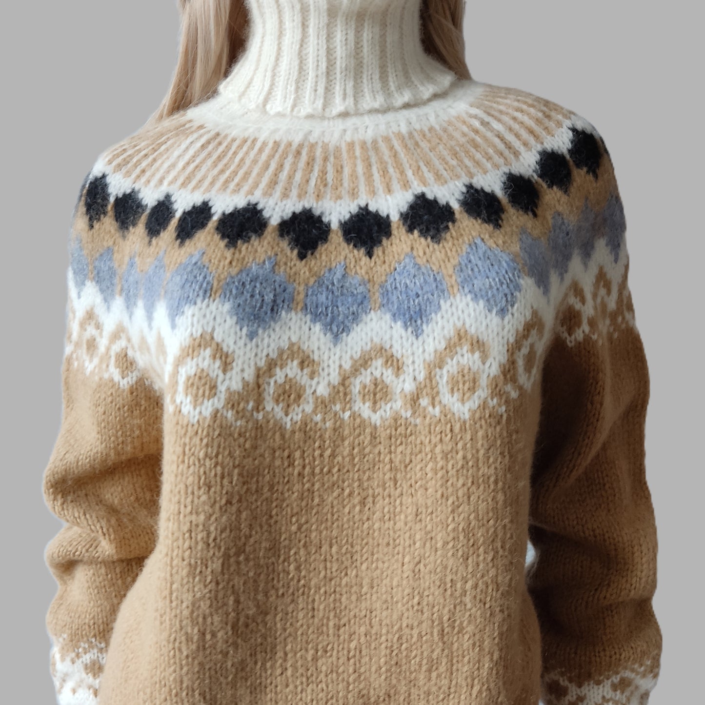 Beige sweater with a patterned neckline on a neutral background