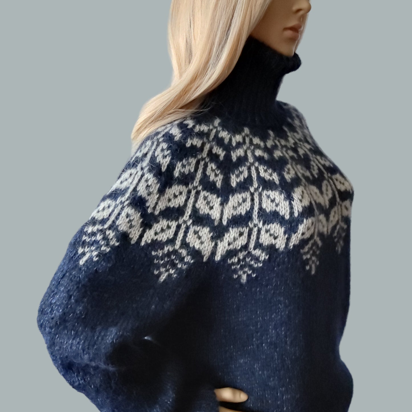 Mannequin wearing a blue sweater with a white pattern on a gray background