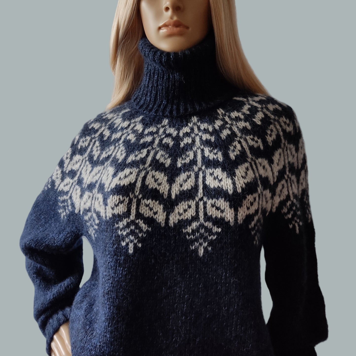 Navy blue sweater with a white pattern on a mannequin against a gray background