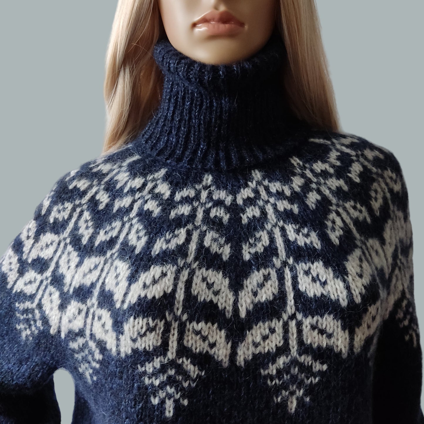 Mannequin wearing a blue and white patterned sweater against a gray background