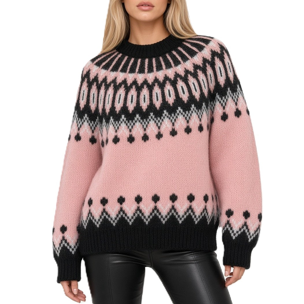 A woman wearing a pink knit sweater with a black and white geometric Fair Isle pattern, paired with black faux leather pants, against a plain white background.