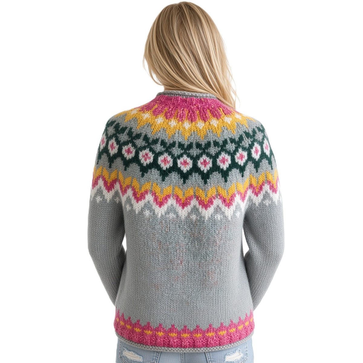 A woman viewed from behind wearing a light blue knit sweater with a colorful Fair Isle pattern in pink, yellow, green, and white. She is wearing light blue jeans against a plain white background.