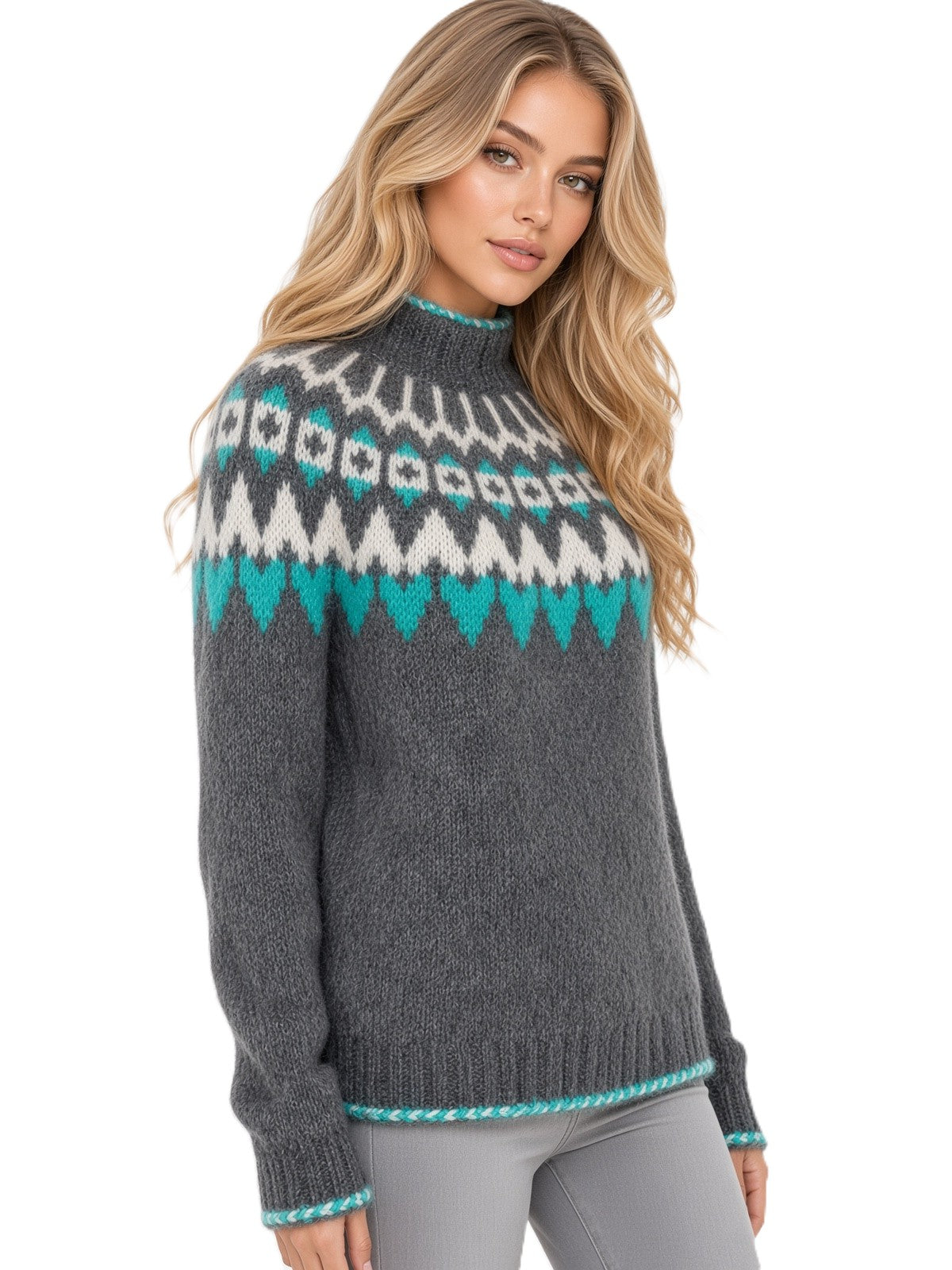 A woman wearing a dark gray knit sweater with a white and teal geometric Fair Isle pattern across the chest and shoulders, paired with gray pants, against a plain white background.