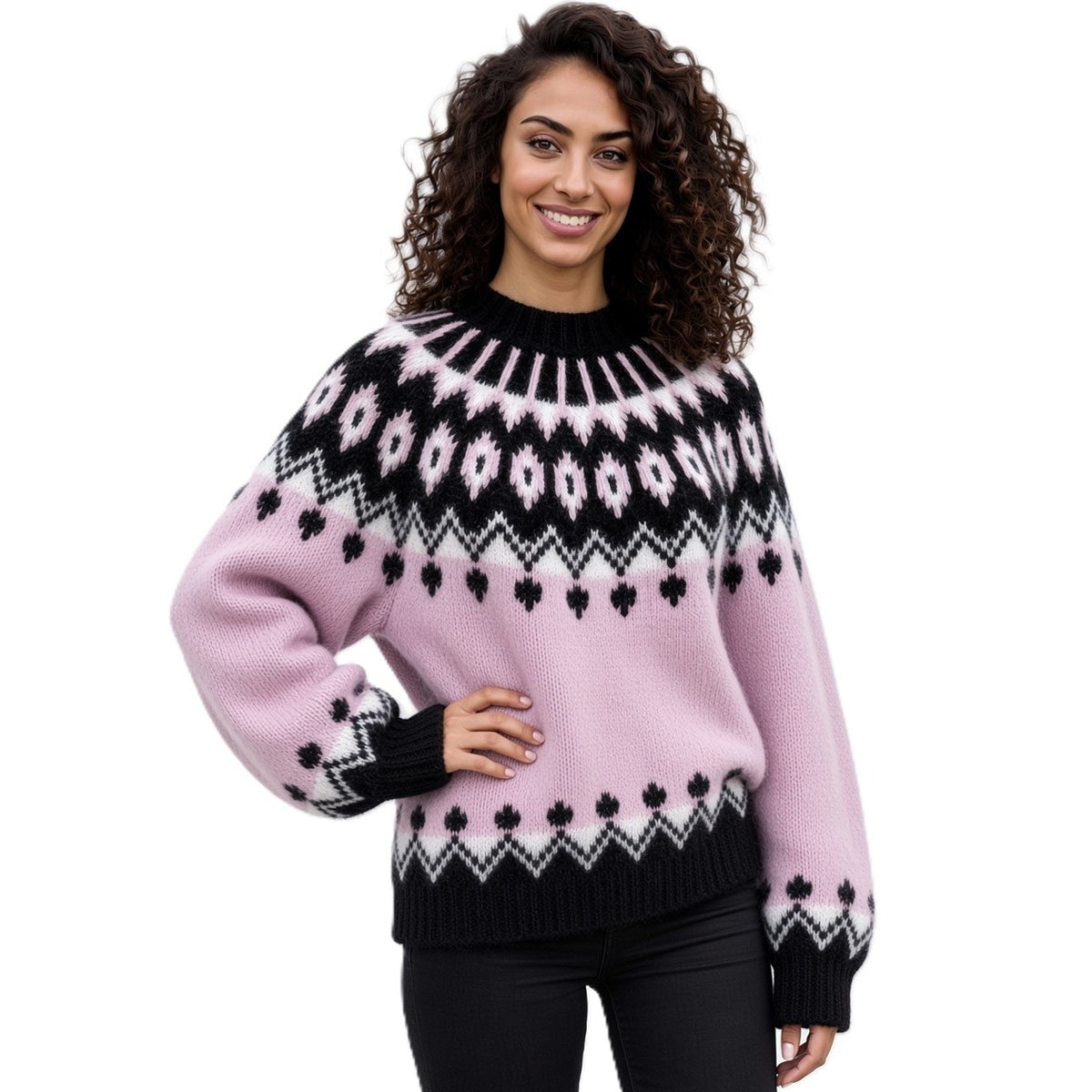 A woman wearing a pink Fair Isle knit sweater with black and white geometric patterns, paired with black pants, against a plain white background.
