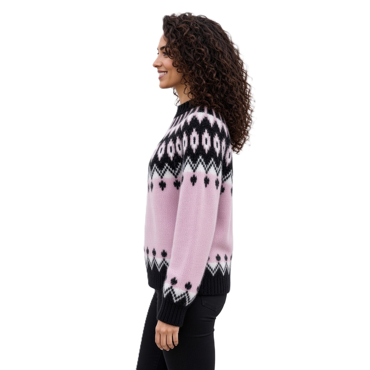 A woman with curly brown hair is shown in profile wearing a pink knit sweater with a black and white Fair Isle pattern, paired with black pants, against a solid white background.