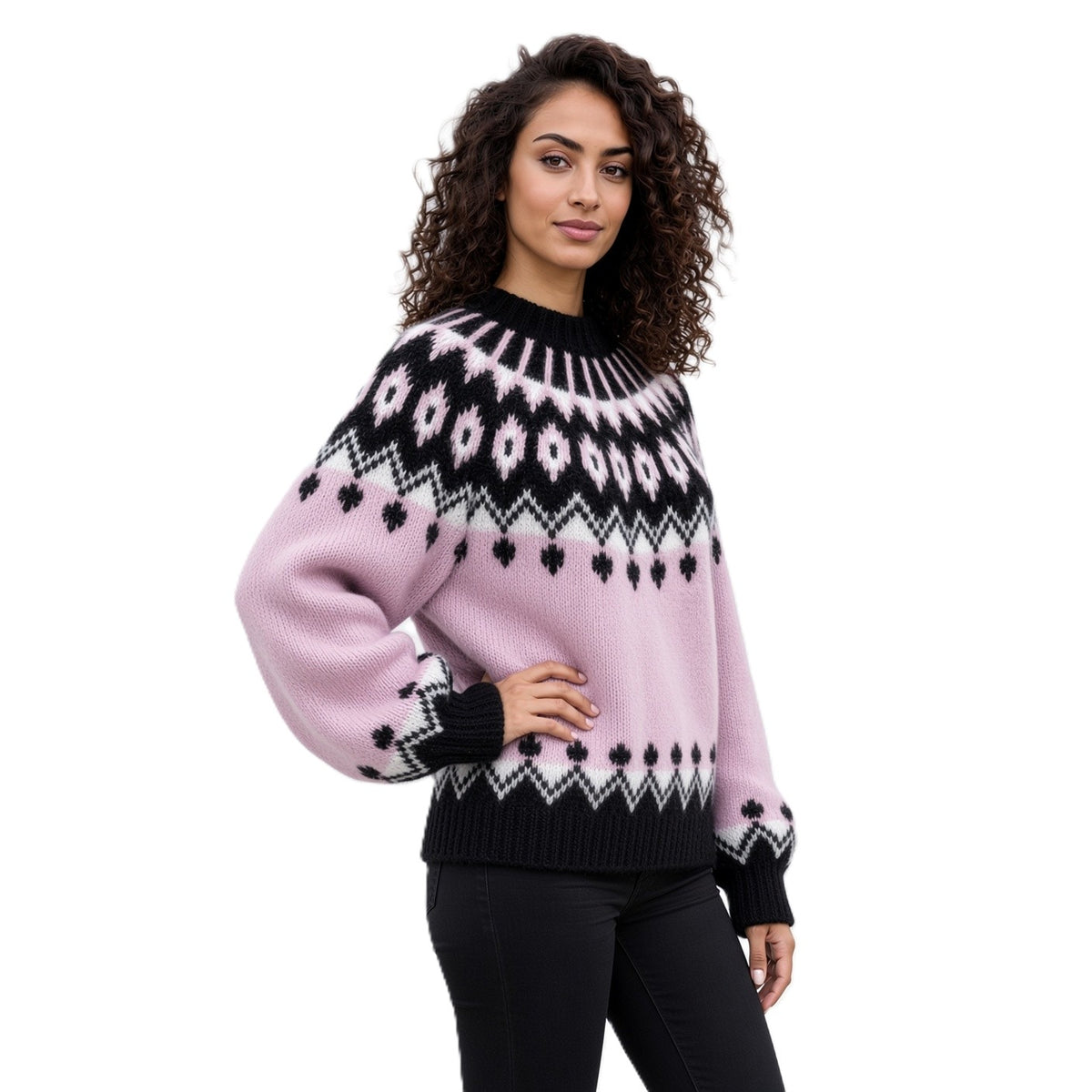 A woman modeling a light pink knit sweater with a black and white Fair Isle pattern across the chest, shoulders, and cuffs, paired with black pants against a solid white background.