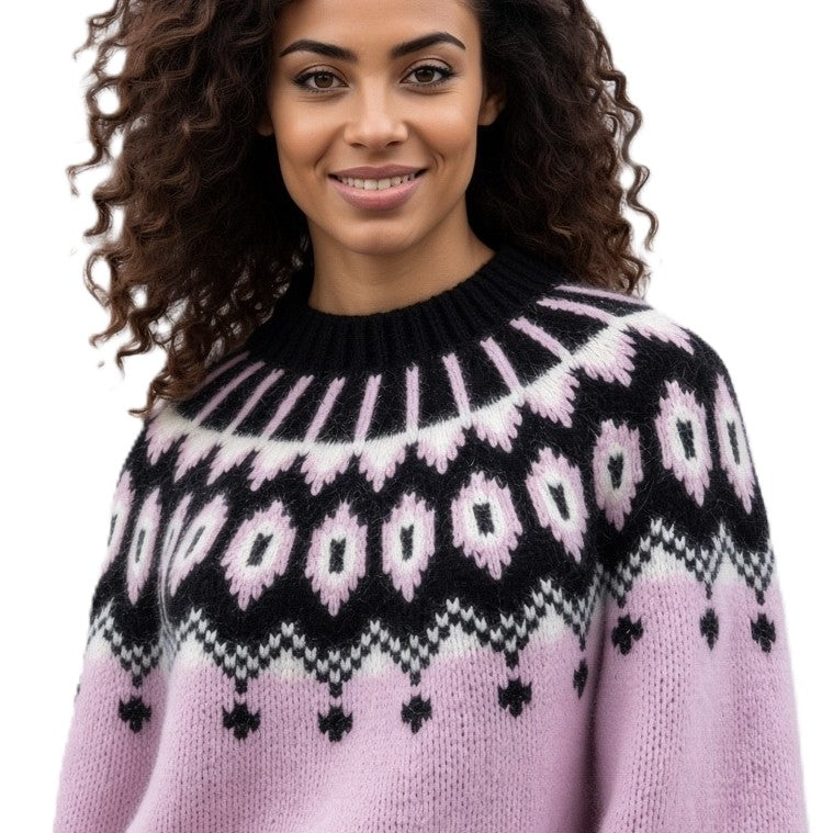 A smiling woman with curly brown hair wearing a knit sweater with a black, white, and light pink Fair Isle pattern, shown against a plain white background.