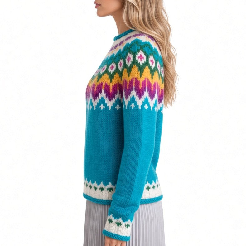 A woman shown from the side wearing a bright turquoise knit sweater with a multicolor Fair Isle pattern across the chest and cuffs, paired with a pleated gray skirt against a white studio background.