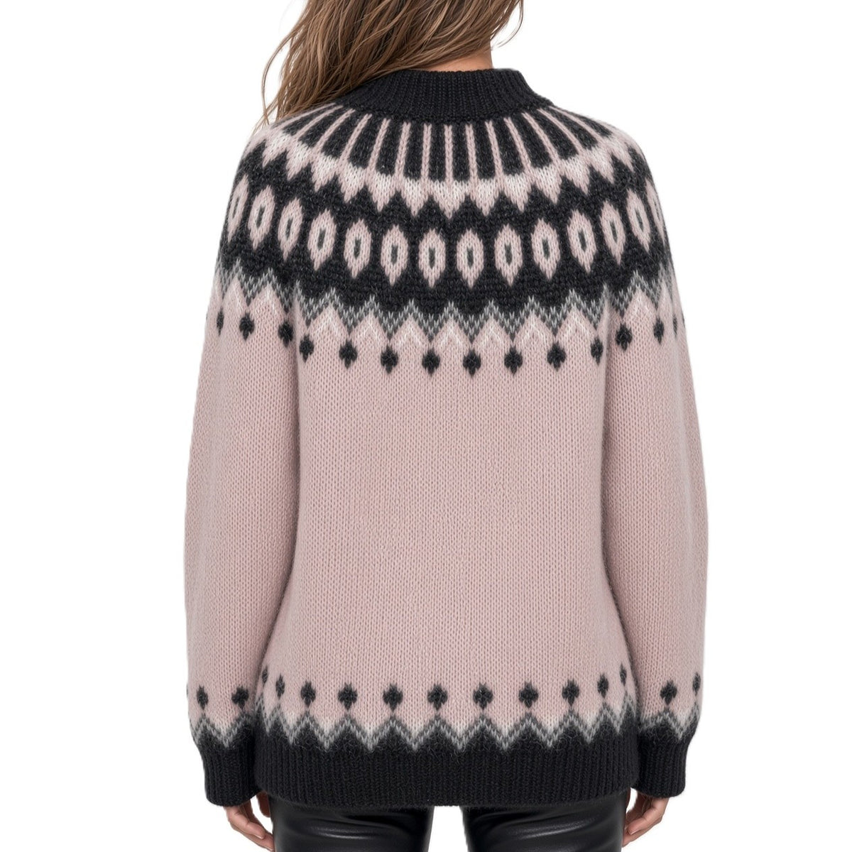 A woman viewed from the back wearing a pink Fair Isle knit sweater with black and white geometric patterns, paired with black leather pants against a white studio background.