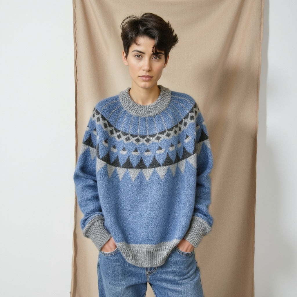 Person wearing a blue and gray patterned sweater against a plain background