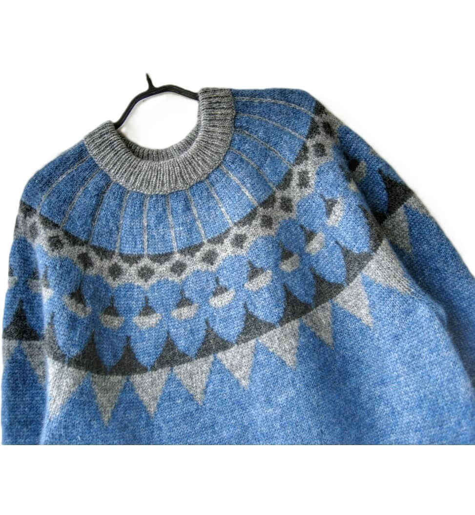 Blue and gray patterned sweater on a hanger against a white background