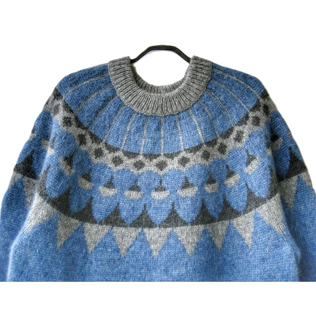 Blue and gray patterned sweater on a hanger against a white background