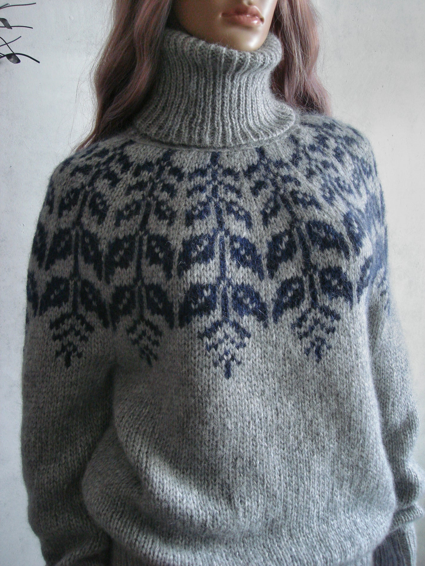 Gray knitted sweater with a pattern on a plain background
